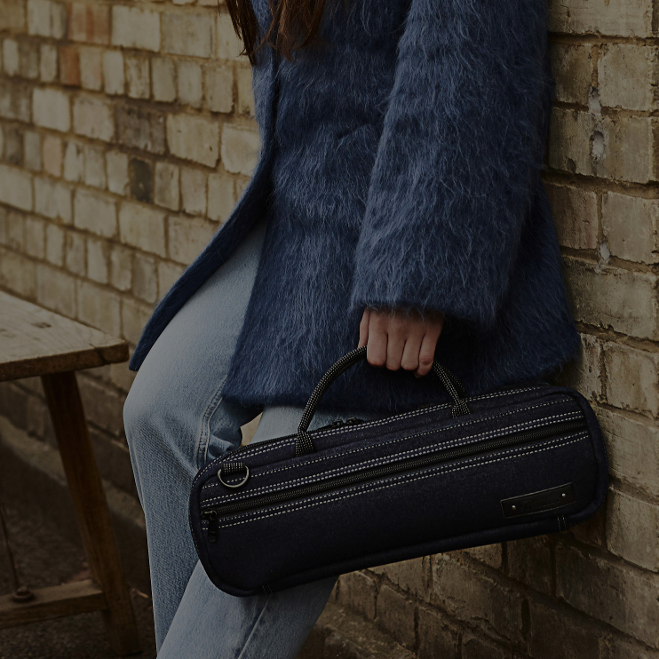 girl leaning against wall with denim flute bag