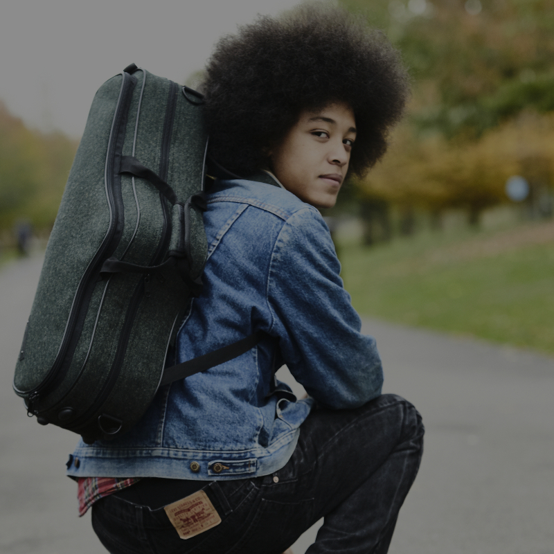 boy crouching with tweed sax case on his back