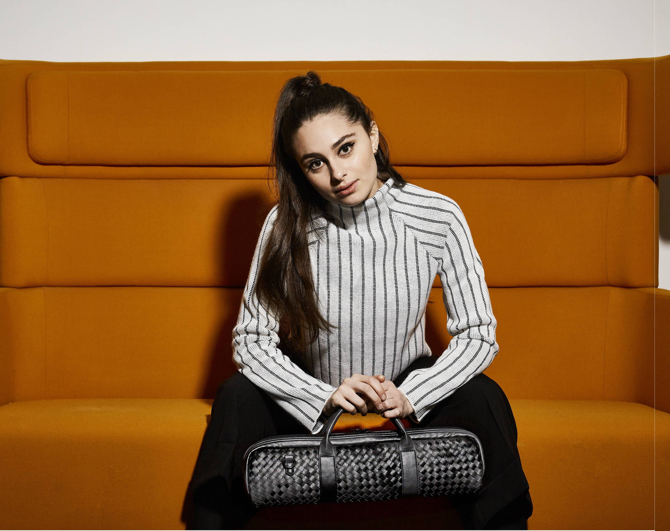 girl sat on orange sofa with flute bag